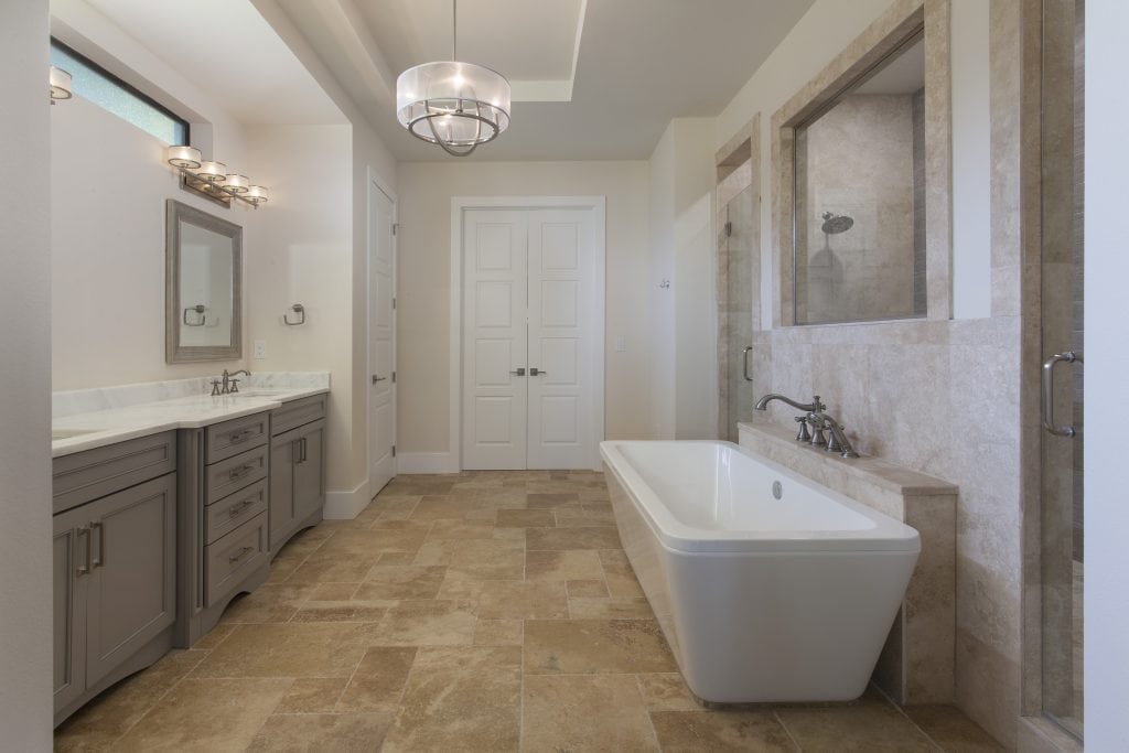 The masterbath features a free standing tub that fronts a double-entry shower with gray base cabinets and white and gray granite countertops in this custom home designed and built by Orlando Luxury Home Builder Jorge Ulibarri. www.imyourbuilder.com