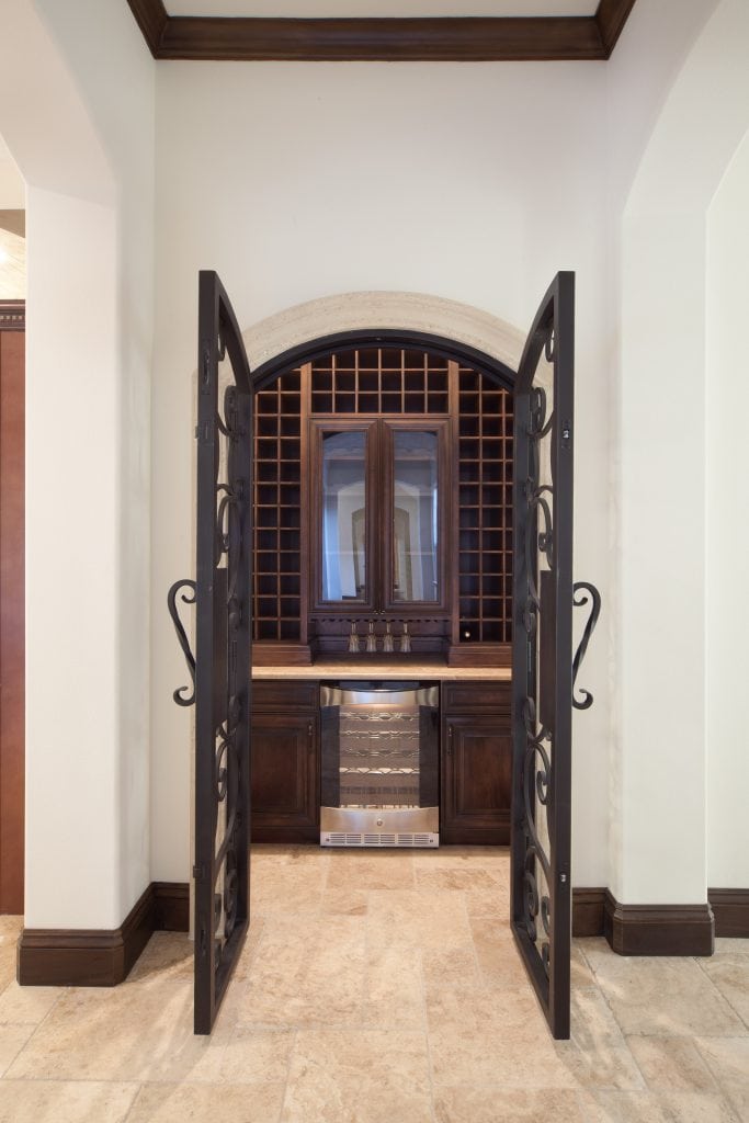 Traditional wine room designed and built by Orlando Custom Home Builder Jorge Ulibarri, owner of Cornerstone Custom Construction. The wine room features custom made wrought iron doors and wine refrigeration. 