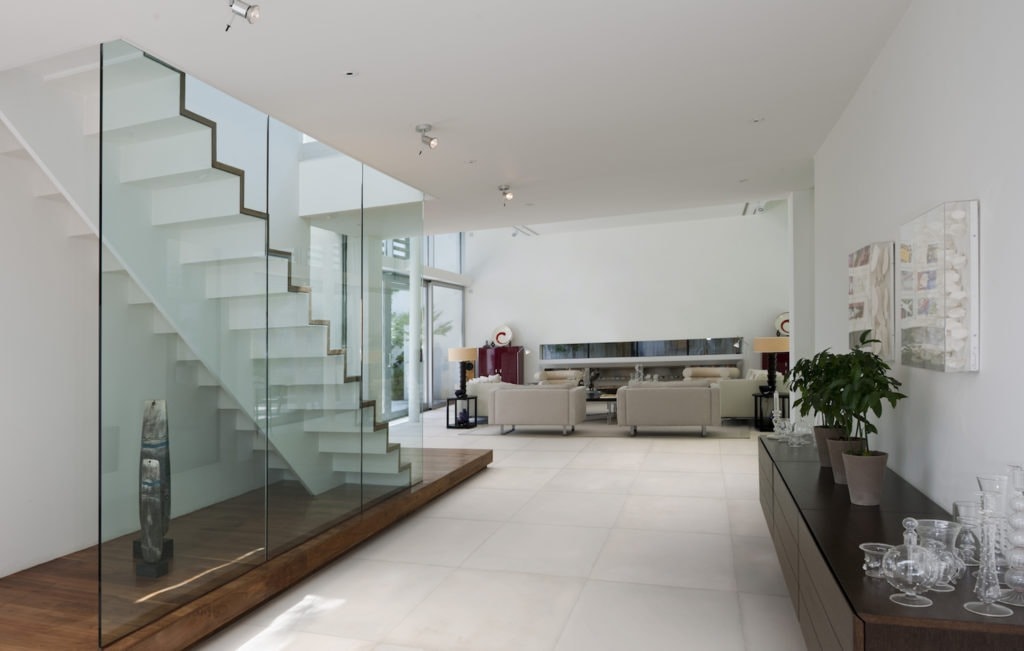 This floating staircase is encased in a glass wall that negates the need for hand railings. For more design ideas by Orlando Custom Home Builder go to www.jorgeulibarri1.wpengine.com