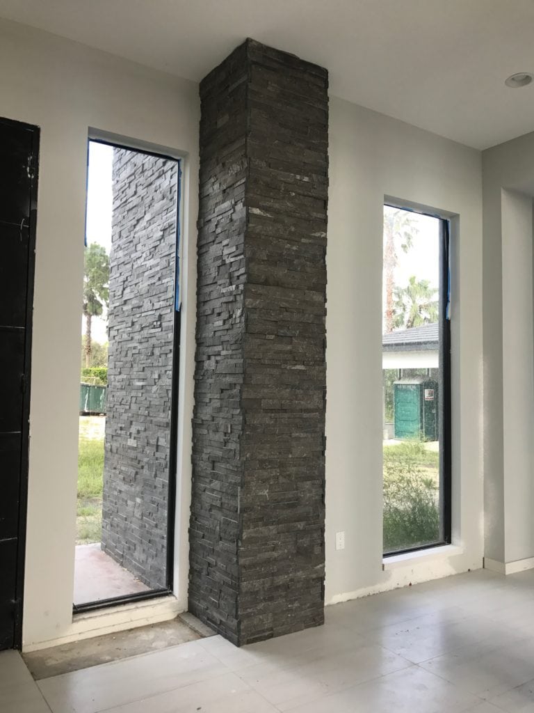 Grey ledge stone on this wall that extends from the exterior to the interior adds warmth to the contemporary styling of this Florida Modern home under construction by Orlando Custom Home Builder Jorge Ulibarri. www.imyourbuilder.com