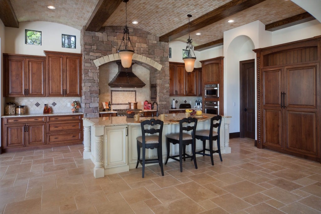 A traditional style kitchen designed and built by Orlando Custom HomeBuilder Jorge Ulibarri draws the eye to the copper range hood framed in stone. www.imyourbuilder.com