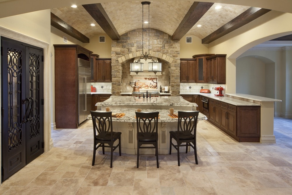 A traditional style kitchen designed and built by Orlando Custom HomeBuilder Jorge Ulibarri showcases an undulating barrel and beam ceiling crafted of travertine tiles and wood beams. The wrought iron double door pantry is another focal point. www.imyourbuilder.com