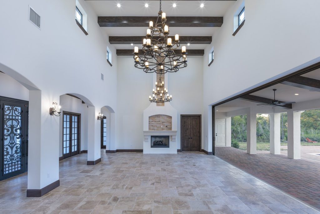 The great room opens to the outdoor living spaces with a 20-foot high ceiling and clerestory windows to draw in natural light from above in this Spanish Revival Custom Home by Orlando Custom Homebuilder Jorge Ulibarri.