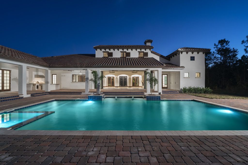 Backyard view of this Spanish Revival custom home by Orlando Custom Homebuilder Jorge Ulibarri that wraps around a pool, spa, outdoor kitchen and living spaces. 