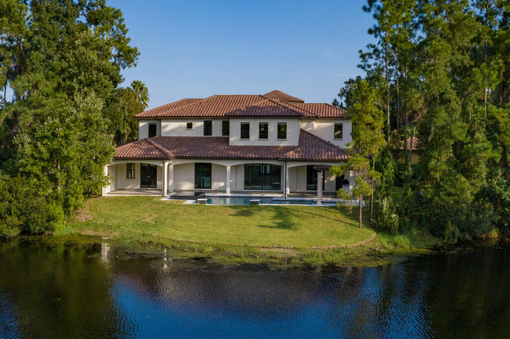 The view from the back of this 5,700 square foot home by Orlando Custom Homebuilder Jorge Ulibarri. The home resides on a half-acre lot with plenty of green spaces for privacy and opens to views of the lake. 