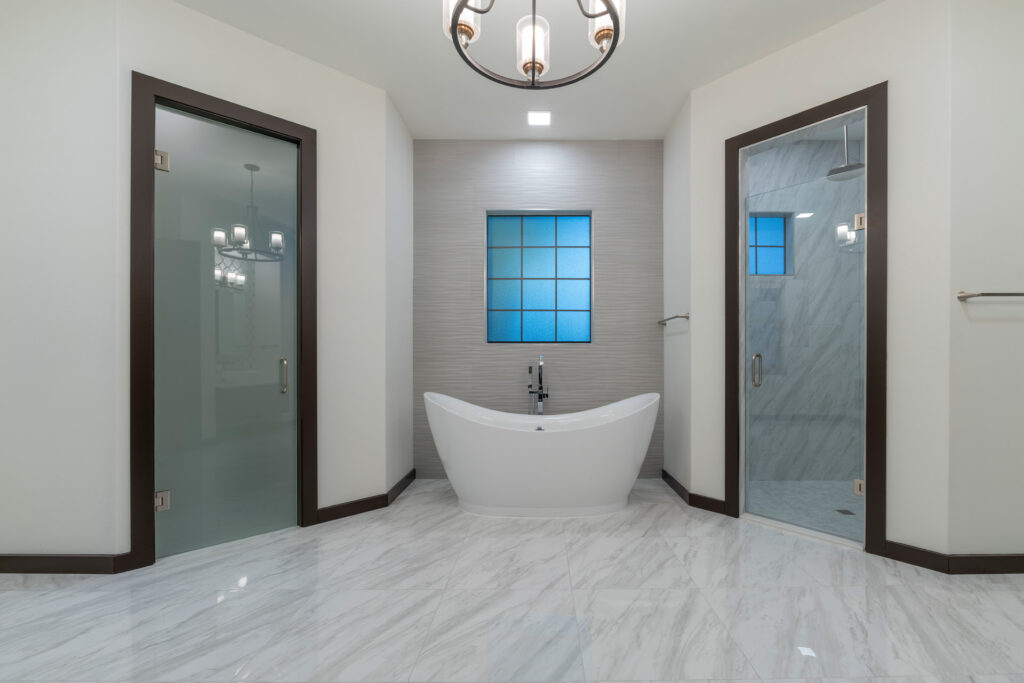 The master bathroom features porcelain tile floors that mimic the look of marble with a niche that frames a free standing tub. 