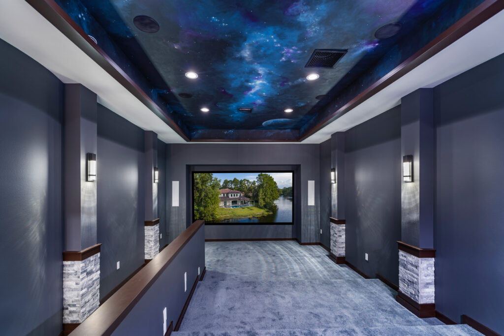The Theater room upstairs showcases a space mural painted on the ceiling with espresso wood trim, dark gray walls and light gray carpet to create the perfect acoustic conditions and ambiance for watching movies on the large screen. 